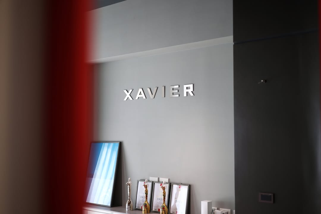 XAVIER 品牌展示空間，灰階微水泥背牆搭配金屬立體字與獎盃陳列